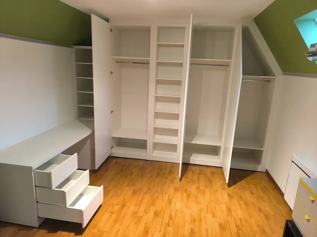 Espace bureau et dressing sous combles avec étagères et tiroirs sur-mesure.